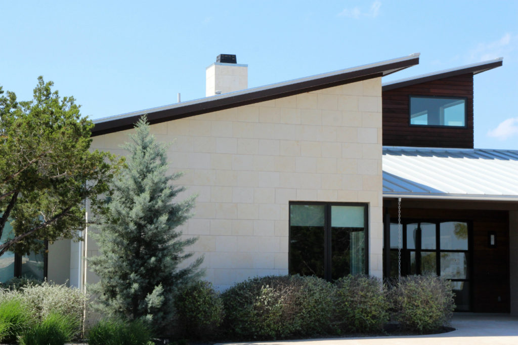 Austin limestone cladding panels are smooth white exterior stone panels on the exterior of a contemporary home